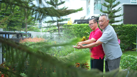 On their day off, the grandfather and grandson help water the trees in the garden of the house