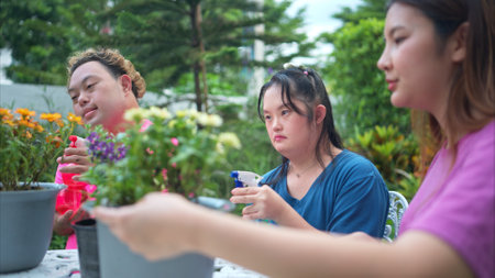On their day off, Three siblings help water and plant flowers in the front yardの写真素材
