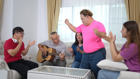 A grandfather with grandchild enjoys singing and dancing together at home during the holidaysの写真素材