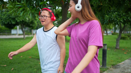 Brother and sister relax and walks while listening to music through headphones in a parkの写真素材