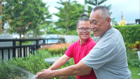 On their day off, the grandfather and grandson help water the trees in the garden of the houseの写真素材