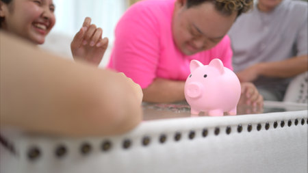 Three siblings save money by putting it in a piggy bank, This is an activity that parents teach their children about saving moneyの写真素材
