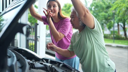 Grandmother and grandchild help each other execute a basic engine check on their parents' automobileの写真素材