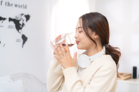 Asian young woman enjoying bread and coffee for breakfast at home, morning routine before workの写真素材