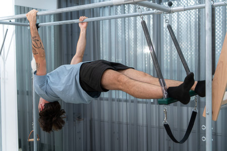 A young man doing pilates exercises on a pilates cadillacの写真素材