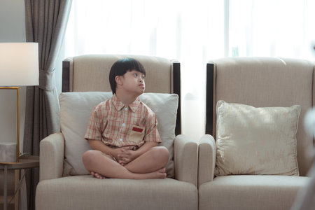A special child relaxes on the sofa in the living room of the houseの写真素材