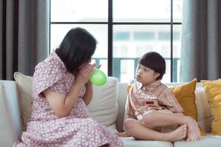 A special child and his mom having fun and relaxing on a holiday together in the living room of the houseの写真素材