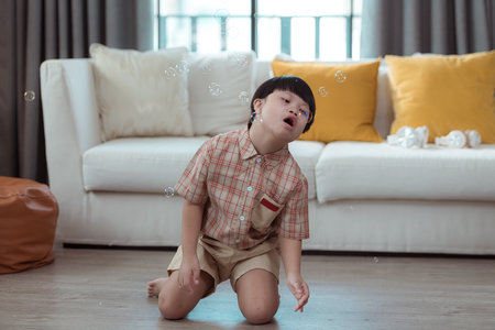A special child having fun playing with a soap bubble bag in the living room of the houseの写真素材
