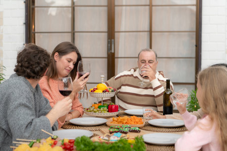 Grandfather, parents, and the teenage girls are all having dinner together at homeの写真素材
