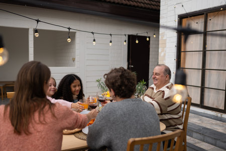 Grandfather, parents, and the teenage girls are all having dinner together at homeの写真素材