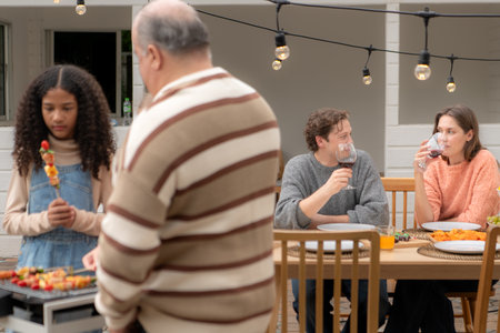 Grandfather, parents, and the teenage girls are all having dinner together at homeの写真素材