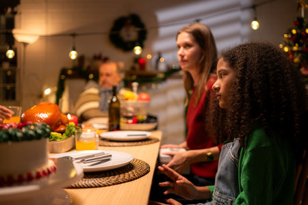 Grandfather, parents, and the teenage girls are all having dinner together at home on Christmas nightの写真素材