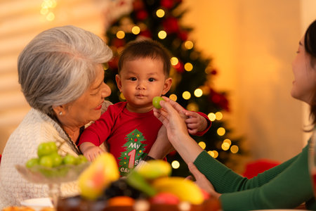 Grandmother, mother and little boy celebrate happily on Christmas nightの写真素材