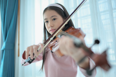 A girl violinist plays and practices the violin at homeの写真素材