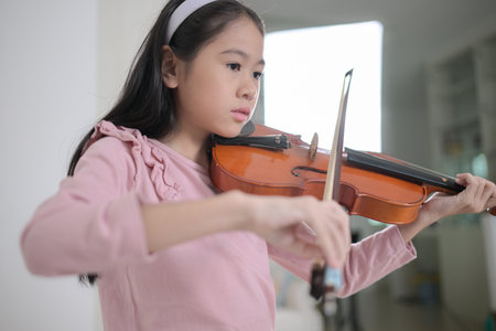 A girl violinist plays and practices the violin at homeの写真素材
