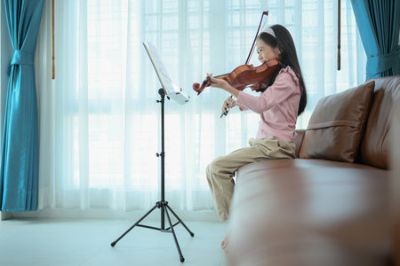 A girl violinist plays and practices the violin at homeの写真素材