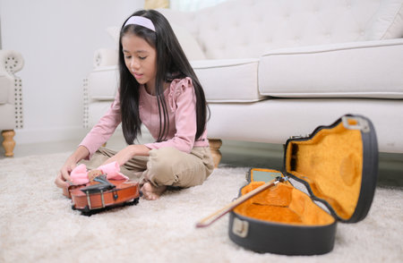 A girl violinist cleans her violin before putting it away in its caseの写真素材