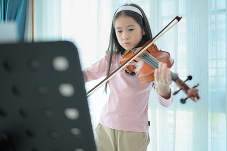 A girl violinist plays and practices the violin at homeの写真素材