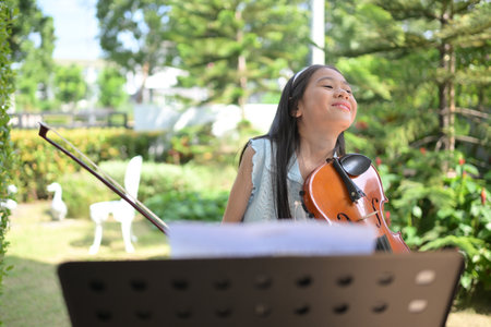 A girl violinist plays and practices the violin in the garden at homeの写真素材