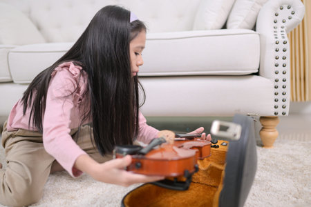 A girl violinist cleans her violin before putting it away in its case