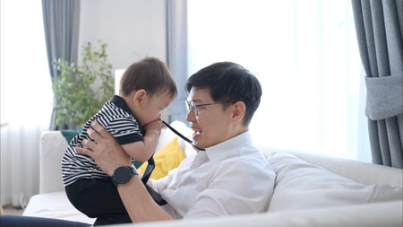 Father and son play together after dad comes home from workの写真素材