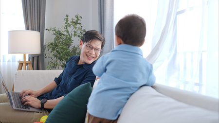 Father and son play together after dad comes home from workの写真素材