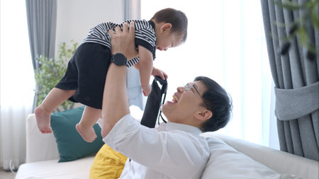 Father and son play together after dad comes home from workの写真素材