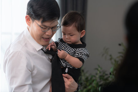 A business father assigns work to his secretary, while also taking care of his child while workingの写真素材