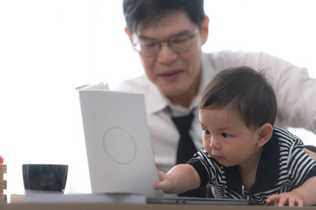 A business father and his duty to take care of his children while workingの写真素材