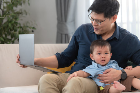 Father and son play together after dad comes home from workの写真素材