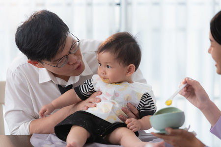 Father and mother feed their son breakfast before going to work in the kitchen of the houseの写真素材