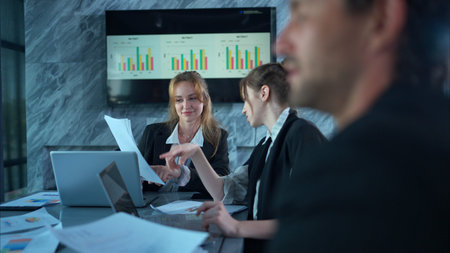 In the conference room, a group of businesspeople are discussing the follow-up meeting and the...