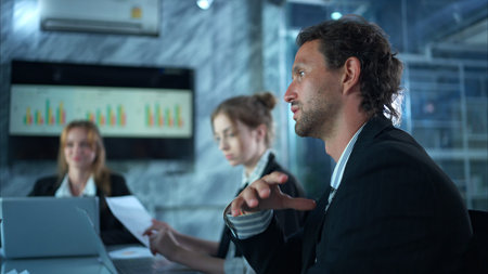 In the conference room, a group of businesspeople are discussing the follow-up meeting and the...