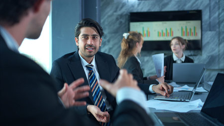 In the conference room, a group of businesspeople are discussing the follow-up meeting and the...