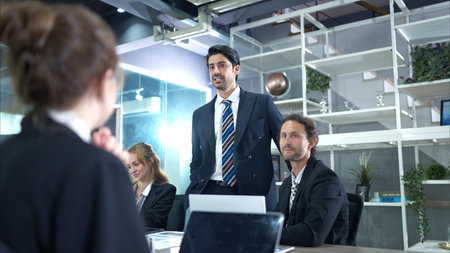 In the conference room, a group of businesspeople are discussing the follow-up meeting and the...