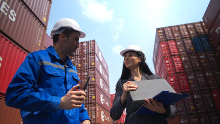 Container manufacturing manager and businesswomen survey the area to plan the storage and moving of...