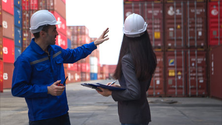 Container manufacturing manager and businesswomen survey the area to plan the storage and moving of...