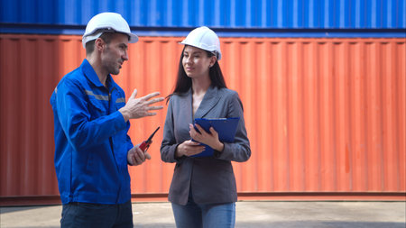 Container manufacturing manager and businesswomen survey the area to plan the storage and moving of...