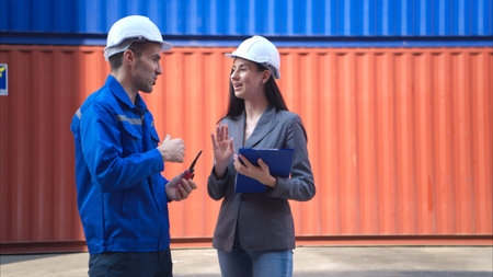 Container manufacturing manager and businesswomen survey the area to plan the storage and moving of...