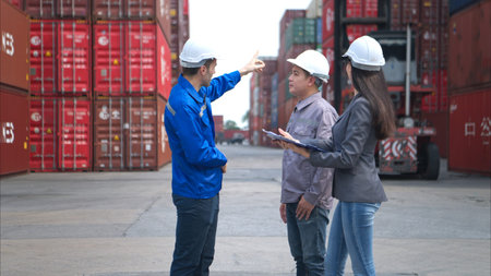 Container manufacturing manager and businesswomen survey the area to plan the storage and moving of...