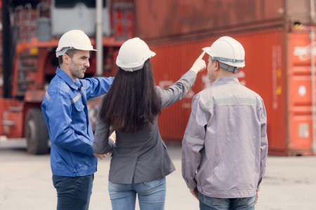 Container manufacturing manager and businesswomen survey the area to plan the storage and moving of...