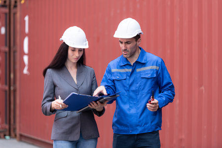 Container manufacturing manager and businesswomen survey the area to plan the storage and moving of goods in and out of the container storage areaの写真素材