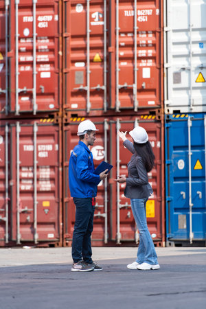 Container manufacturing manager and businesswomen survey the area to plan the storage and moving of...