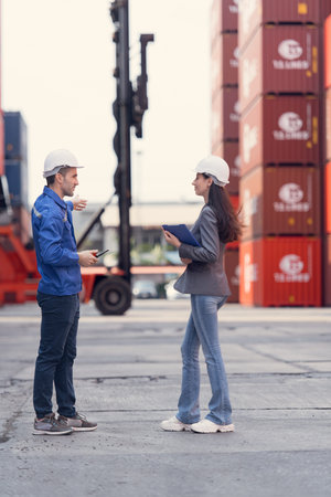 Container manufacturing manager and businesswomen survey the area to plan the storage and moving of...
