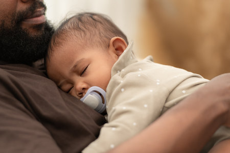 A baby sleeps in his father's armsの写真素材