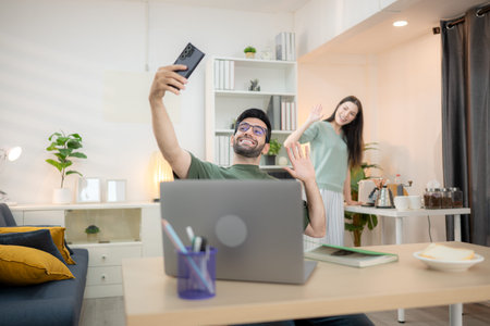 Portrait of a young freelancer smiling while working online via laptop at home with his girlfriend