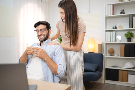 Portrait of a young freelancer smiling while working online via laptop at home with his girlfriendの写真素材