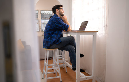 Portrait of a young freelancer smiling while working online via laptop at home with his girlfriend