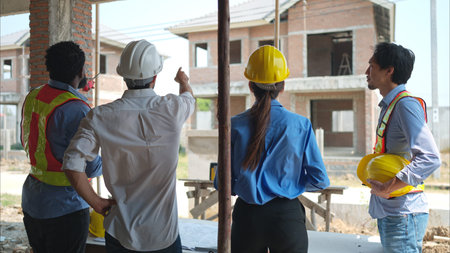 Group of architects and engineers work together to assess the residential home construction site's...