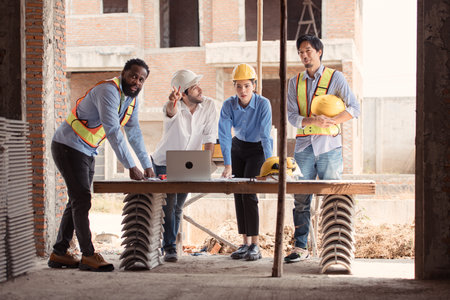 Group of architects and engineers work together to assess the residential home construction site's progressの写真素材